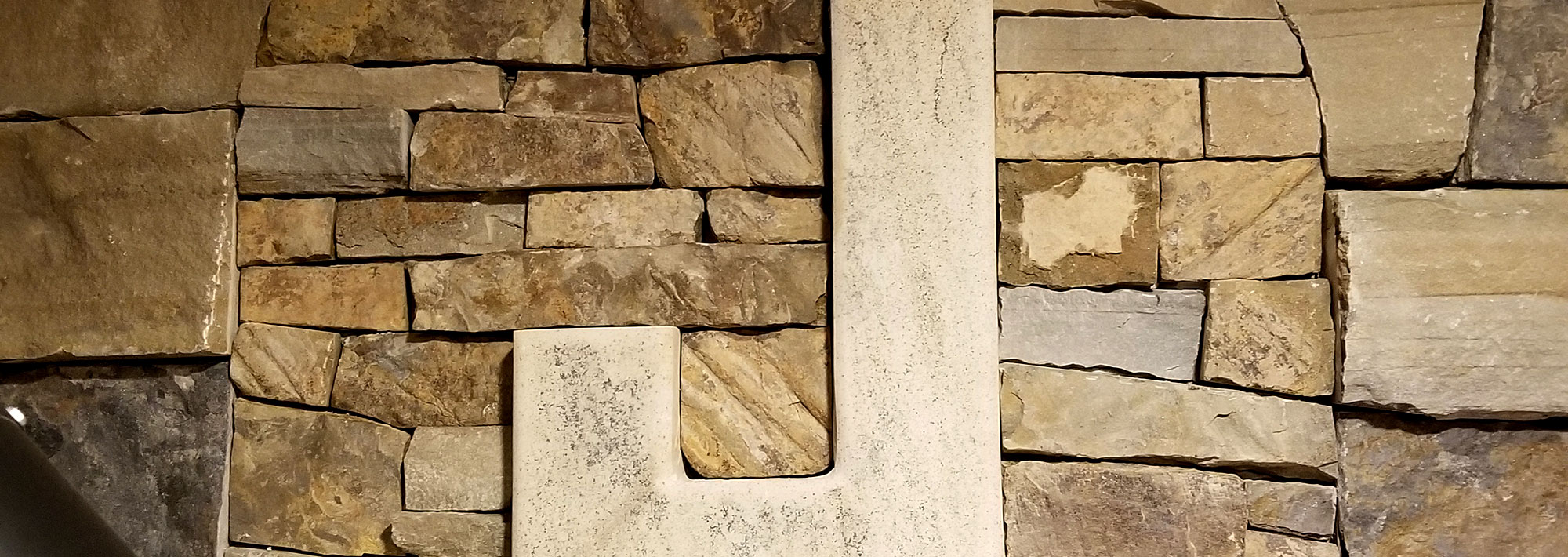 a rock carved into the shape of a J on a stone wall