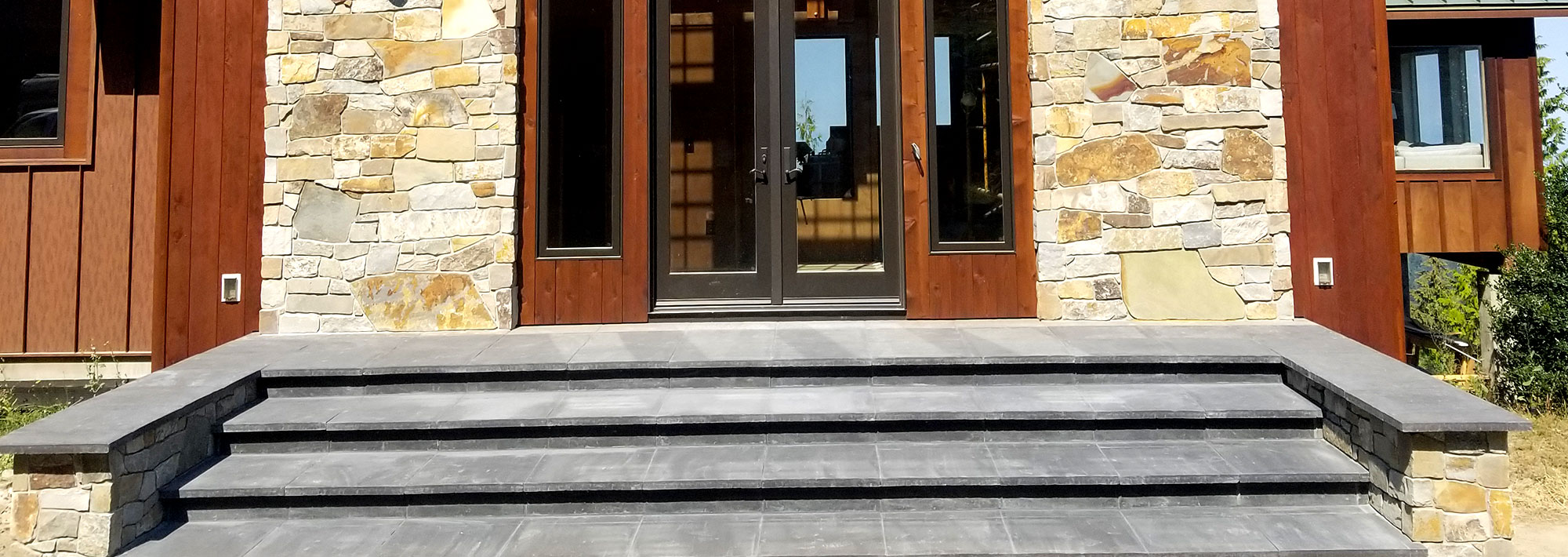 Paver steps in front of a house with stone siding